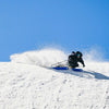 Person skiing down a snowy slope with a clear blue sky on Faction Agent 4 freetouring skis